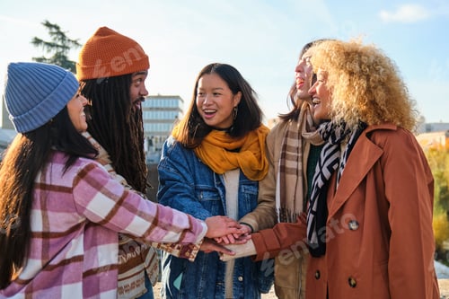 Preview: Happy diverse group of friends holding hands stacking them together outside.