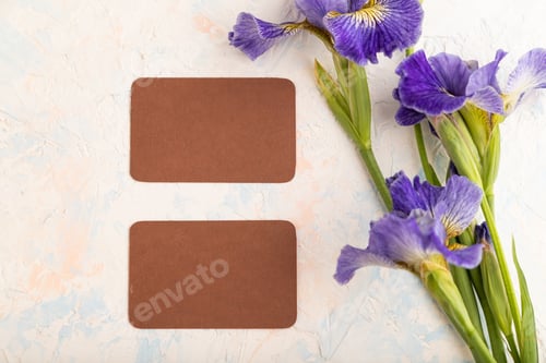 Preview: Brown business card with blue iris flowers on white concrete background. top view, copy space.