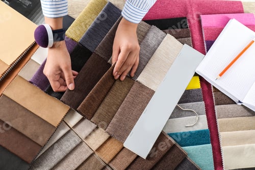 Preview: Young woman choosing among upholstery fabric samples, closeup. Interior design
