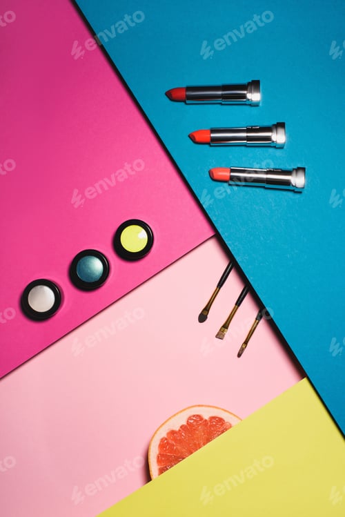 Preview: top view of various makeup supplies with grapefruit slice on colorful surfaces