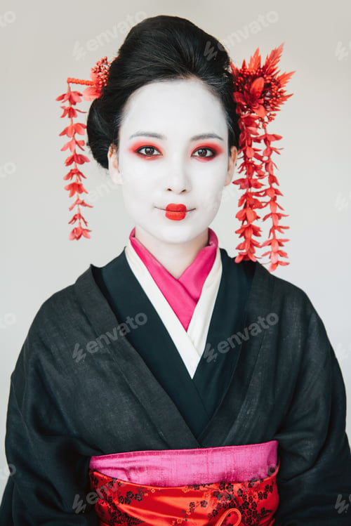 Preview: smiling beautiful geisha in black kimono with red flowers in hair isolated on white