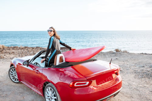 Preview: Woman with surfboard on the car near the ocean