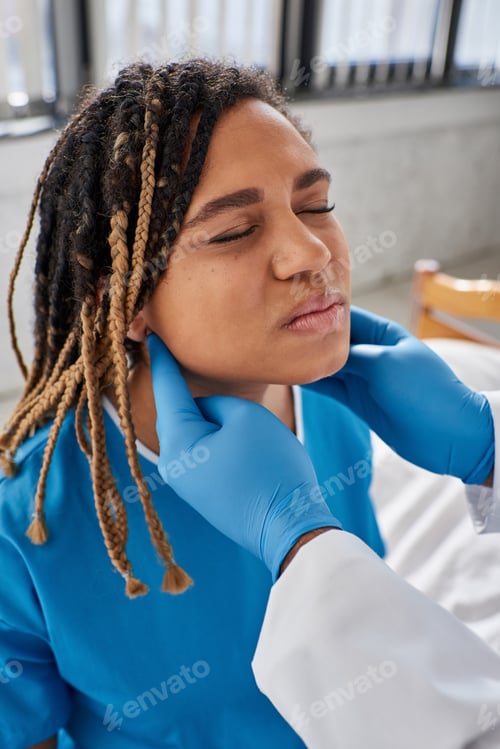Preview: young indian doctor examining lymph nodes of his ill african american female patient, healthcare