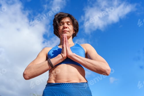 Preview: Woman practicing yoga with prayer hands pose outdoors, finding inner peace and mindful energy