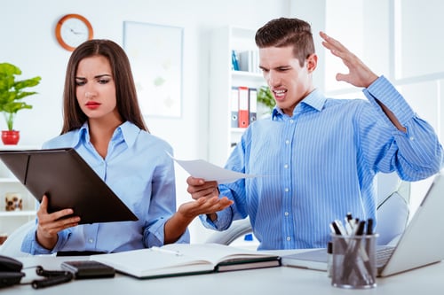 Frustrated Business Colleagues at Desk with Papers