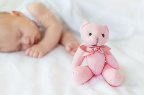 Preview: Baby sleeps with a teddy bear on a white background. Selective focus.