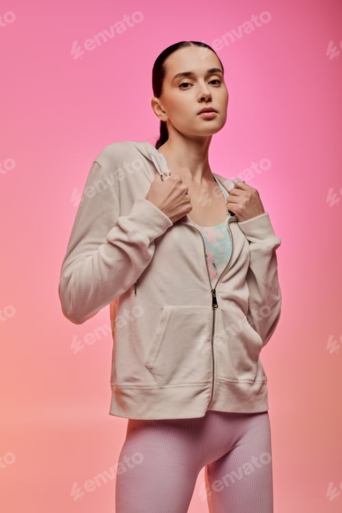 Preview: Stylish young woman showcases modern fashion against a vibrant pink backdrop