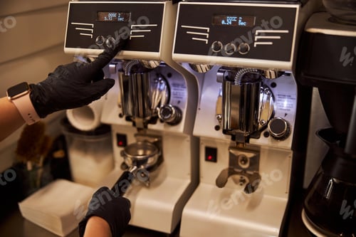 Preview: Experienced barista using modern coffee-grinder at work