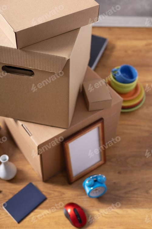 Preview: Cardboard boxes and things for moving to new home. Stack of cardboard box on floor background.