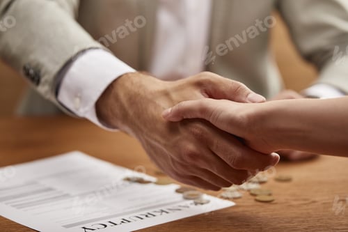 Preview: cropped view of businessman and businesswoman shaking hands at wooden table