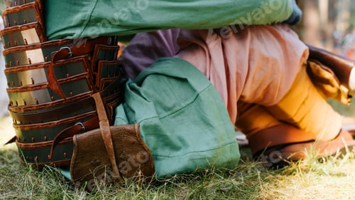 Preview: Close-up of a warrior wearing a medieval costume, armor and a leather bag on his belt sitting