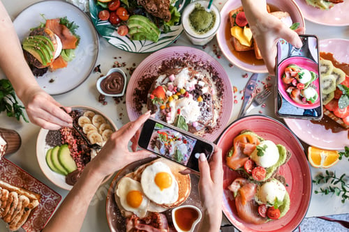 Preview: Friends taking pictures of food on the table with smartphones during brunch in restaurant