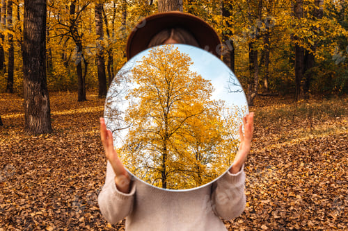 Preview: Woman holding a mirror with a tree reflected. Autumn mood, creative art photography.