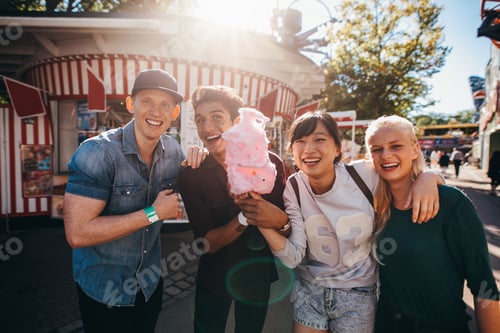 Preview: Group of young friends with cotton candy in amusement park