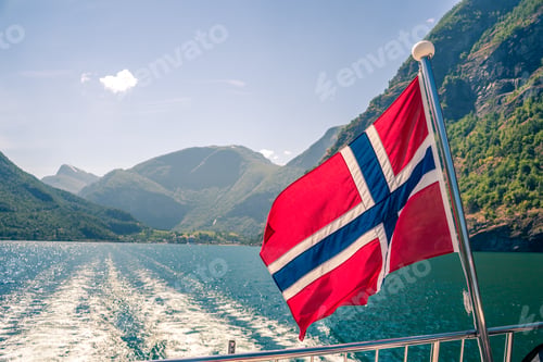 Preview: Beautiful lake view with the Norwegian flag flying on the aft deck of the fjord cruise ship