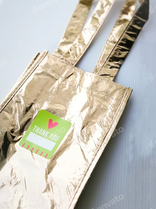 Preview: thank you written on the label of a gold metallic tote bag