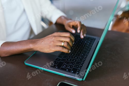 Preview: Focused Freelancer Typing on Teal Laptop in Bustling Coffee Shop