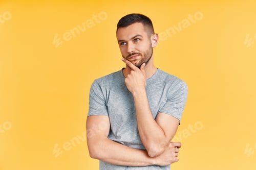 Preview: Young thoughtful man thinking and looking aside on copy space isolated on yellow background