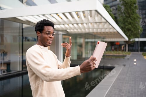Preview: Young businessman having a video call on tablet in a business center