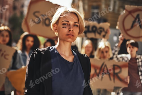 Preview: Young blonde woman with word love written on her face protesting