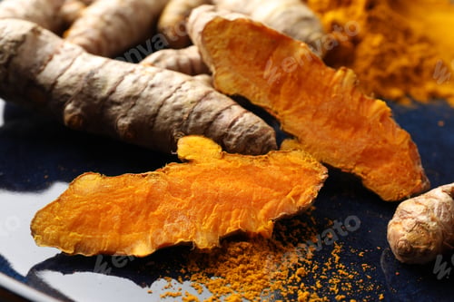 Preview: Aromatic turmeric powder and fresh roots on blue plate, closeup