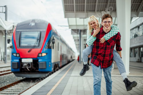 Preview: Young couple piggyback riding while having fun together on a train station