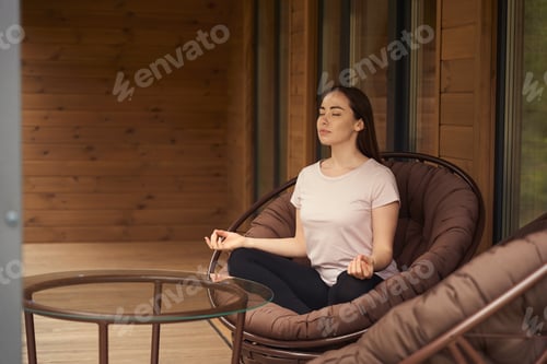 Preview: Woman Meditating in a Wicker Chair Indoors