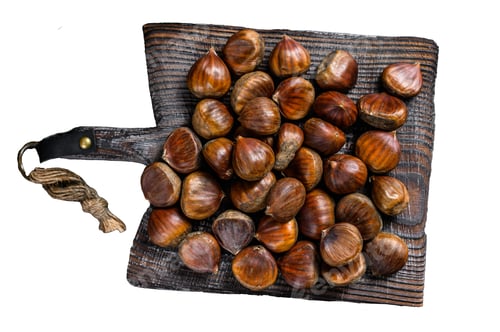 Preview: Raw chestnuts on a wooden cutting board. Isolated on white background, top view.
