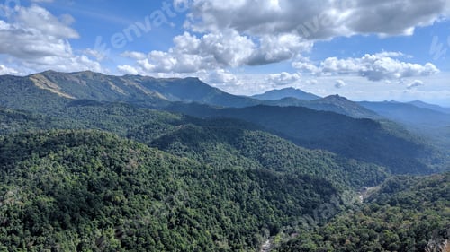 Preview: Lush green mountains under a partly cloudy sky.