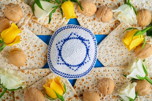 Preview: Passover celebration concept. Blue Star of David made from matzah, white and yellow roses, kippah an