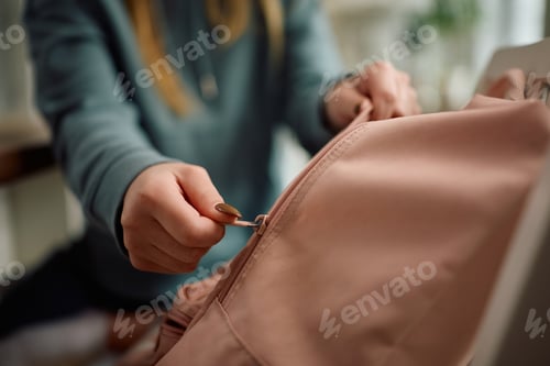 Preview: Close up of girl unpacking her schoolbag at home.