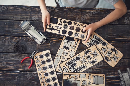 Preview: Horizontal Photo Of Wooden Constructor In The Hands Of A Child Sitting At The Table