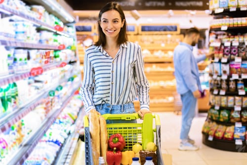 Preview: Young smiling woman shopping in supermarket with trolley cart