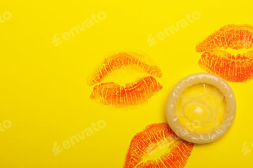 Preview: Condom with lipstick kiss marks and space for text on yellow background, top view. Safe sex