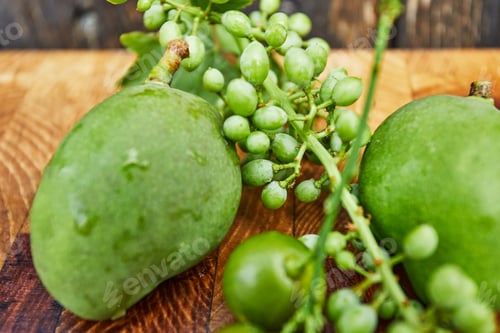 Preview: Fresh green unripe grapes, tangerines and mangoes on a wooden background