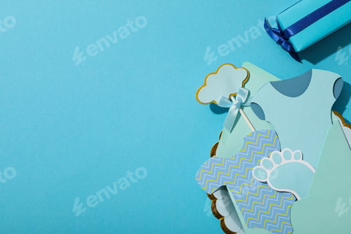 Preview: Envelope with paper baby things and gift box on blue background, space for text