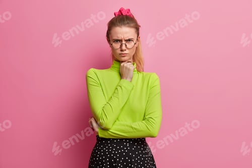 Preview: Dissatisfied grumpy girl looks offended at camera keeps hand under chin doesnt agree with someones o