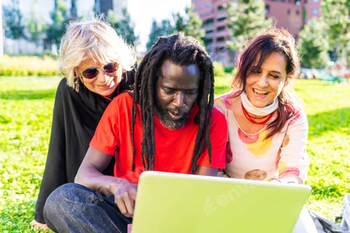 Preview: Friends sharing a moment around a laptop in the park.