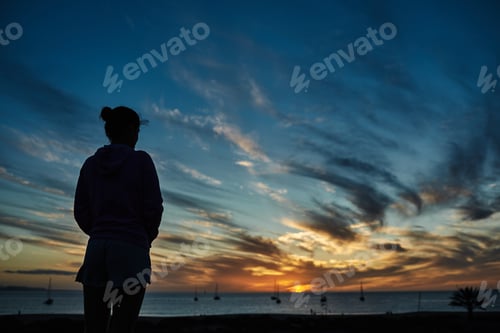 Preview: Woman standing by the beach with sunset on background - Focus on female silhouette