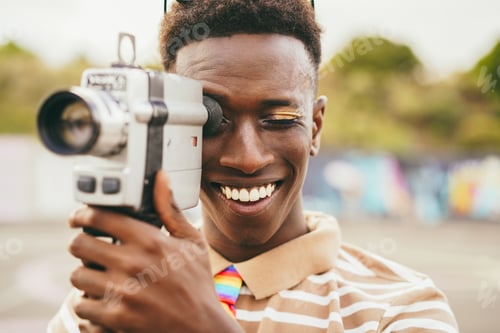 Preview: Young african man using vintage old video camera outdoor