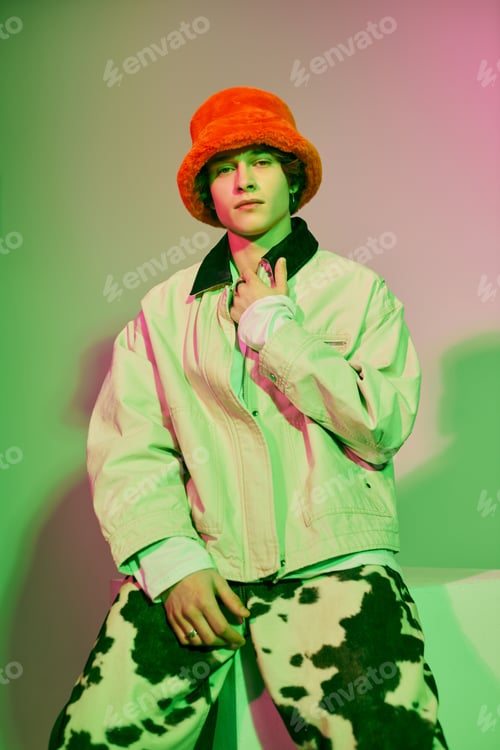 Preview: Fashion forward young man showcasing modern style in vibrant, artistic lighting setting