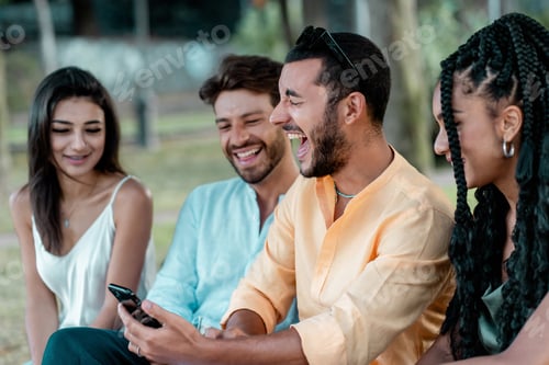 Preview: Young diverse friends laughing together while looking at a smartphone outdoors