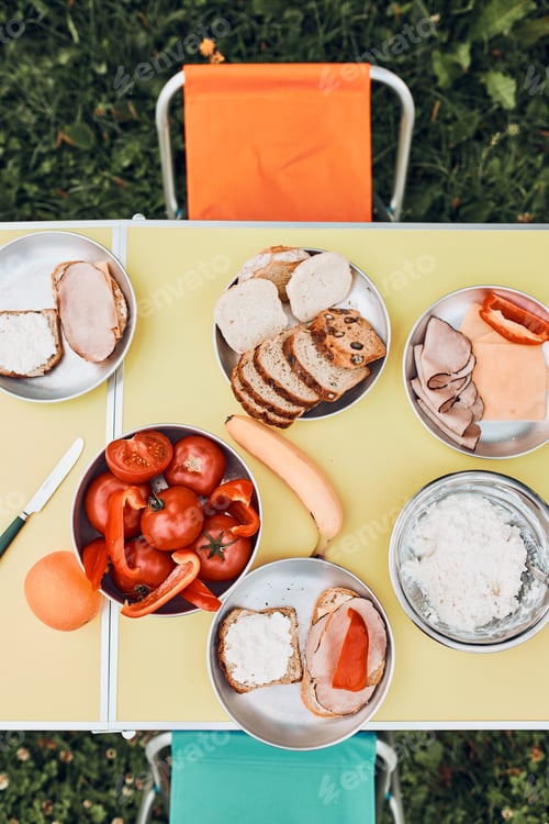 Preview: Breakfast prepared during summer vacation on camping. Bread, cottage cheese, cold meat, tomatoes