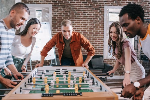 Preview: excited multicultural businesspeople playing table football in office