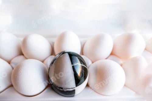 Preview: Eggs of different colors in cardboard boxes. marble stone egg on a background of white chicken eggs