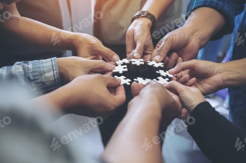 Preview: Closeup image of many people hands holding a jigsaw puzzle in circle together