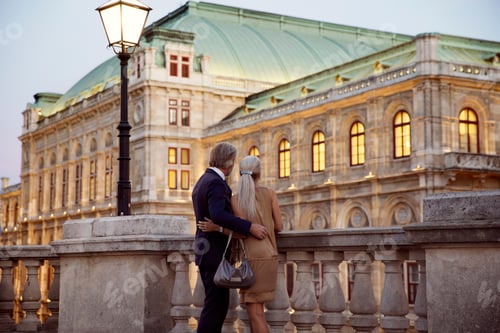 Preview: Elderly couple enjoying a sunset walk by a historic building.