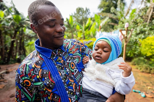 Preview: Proud young African father looking fiercely to his son in his arms