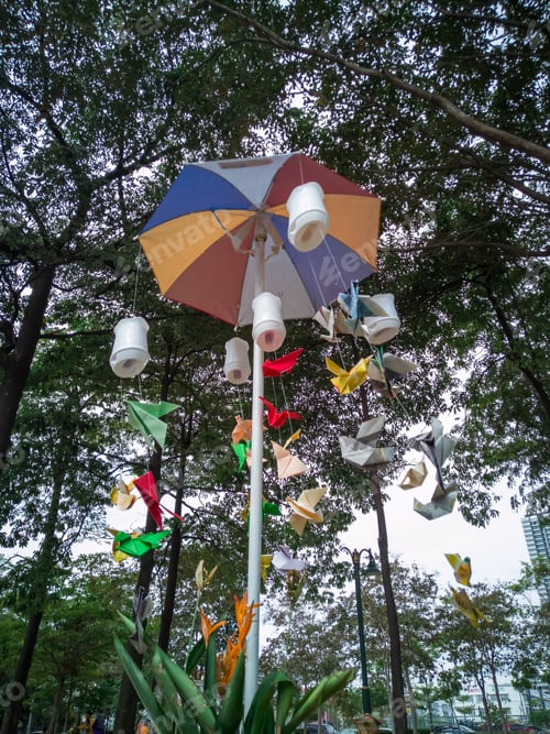Vista previa: recycled bottles hanging from old umbrella as garden decor. low angle view