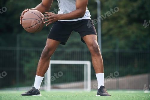 Preview: Close up view. Young black man is with basketball ball outdoors